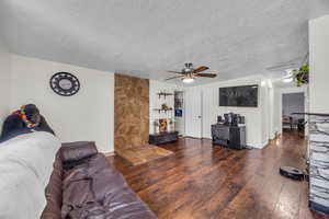 Living area with a textured ceiling, hardwood / wood-style flooring, and a ceiling fan