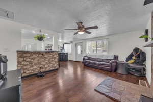 Living area with a ceiling fan, wood-type flooring, and a textured ceiling