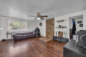 Living room with a ceiling fan, hardwood / wood-style floors, and a textured ceiling