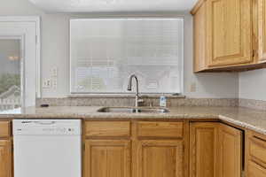 Kitchen with dishwasher and light stone counters