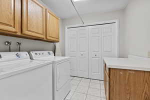 Laundry room with cabinet space, washer and clothes dryer, and light tile patterned flooring
