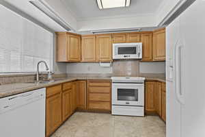 Kitchen with white appliances, crown molding, light countertops, and light tile patterned floors