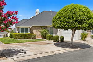 View of front of house featuring driveway, brick siding, roof with shingles, a chimney, and a garage
