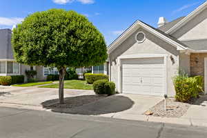 View of front of home with an attached garage, stucco siding, driveway, roof with shingles, and a front yard