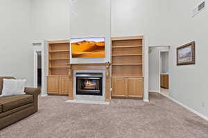 Carpeted living area with a high ceiling and a tiled fireplace