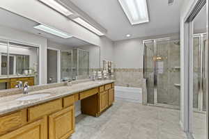 Bathroom featuring double vanity, a stall shower, a bath, and recessed lighting