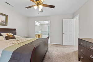 Bedroom with light colored carpet, connected bathroom, a ceiling fan, and a skylight