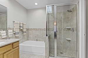 Bathroom featuring vanity, a garden tub, a shower stall, tile patterned floors, and tile walls