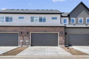 View of front of house with driveway, an attached garage, brick siding, and a shingled roof