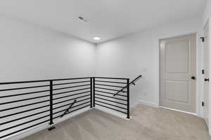 Hall featuring an upstairs landing and carpet flooring