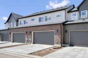 View of front facade with an attached garage, driveway, brick siding, and a shingled roof