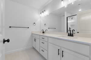 Bathroom featuring double vanity, tile patterned flooring, and a shower