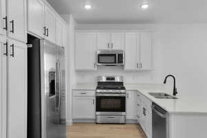 Kitchen with appliances with stainless steel finishes, light countertops, light wood-style flooring, white cabinets, and recessed lighting