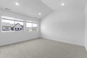 Empty room featuring lofted ceiling, light colored carpet, and recessed lighting