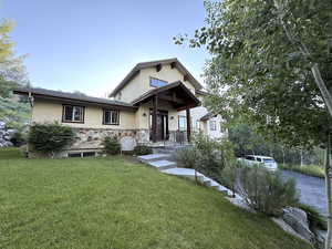 View of front of property featuring stucco siding, a front lawn, and stone siding