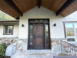Doorway to property with stone siding and stucco siding