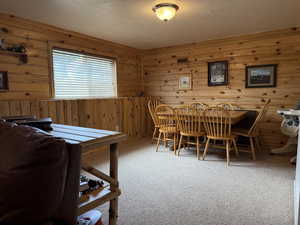 Carpeted dining space with wood walls and a textured ceiling