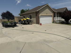 View of home's exterior with a storage unit, stucco siding, concrete driveway, an attached garage, and brick siding