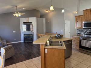 Kitchen with open floor plan, appliances with stainless steel finishes, lofted ceiling, decorative backsplash, and a center island