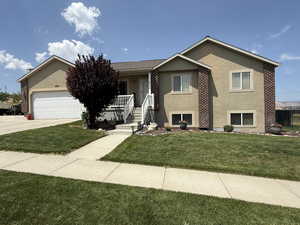 View of front of home with stucco siding, driveway, an attached garage, a front yard, and a porch