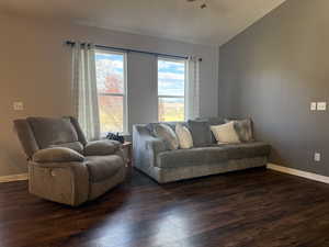 Living area featuring vaulted ceiling and dark wood-style flooring