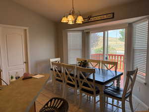 Dining space with a chandelier, light tile patterned flooring, and vaulted ceiling