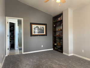 Unfurnished bedroom with lofted ceiling, carpet, a textured ceiling, and ceiling fan