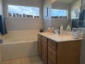 Bathroom featuring a garden tub, vanity, and light tile patterned floors