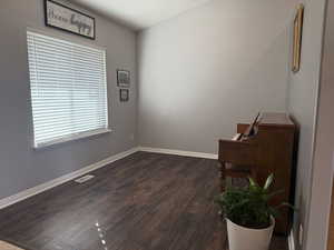 Empty room with dark wood-style floors and baseboards