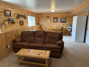 Living room featuring light colored carpet, wood walls, and a textured ceiling