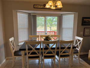 Tiled dining area featuring a chandelier and baseboards