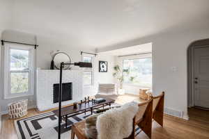 Living area with arched walkways, wood finished floors, and a brick fireplace