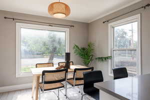 Dining space featuring healthy amount of natural light, crown molding, and light wood-style floors