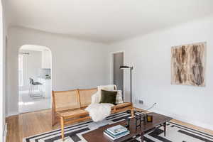 Sitting room featuring arched walkways, light wood-type flooring, and a baseboard radiator