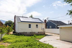 Back of house featuring a patio area, roof mounted solar panels, a chimney, and roof with shingles