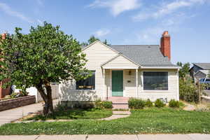 Bungalow with a chimney, roof with shingles, and a front yard