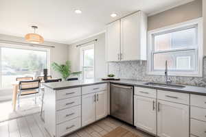 Kitchen featuring stainless steel dishwasher, plenty of natural light, backsplash, a peninsula, and ornamental molding