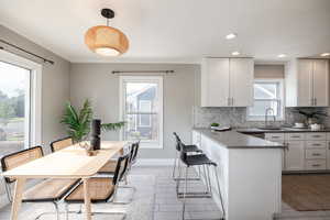 Kitchen with tasteful backsplash, plenty of natural light, a peninsula, white cabinets, and ornamental molding