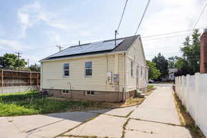 View of home's exterior featuring solar panels and roof with shingles