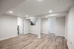 Finished basement with recessed lighting, light wood finished floors, stairs, and washer / dryer