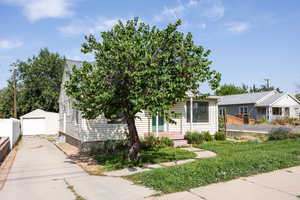 View of front of house with a detached garage, concrete driveway, and an outbuilding