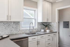 Kitchen with dishwasher, white cabinetry, electric panel, and decorative backsplash