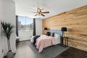 Bedroom featuring wood walls, wood finished floors, and ceiling fan