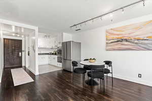 Dining area with dark wood-type flooring and track lighting