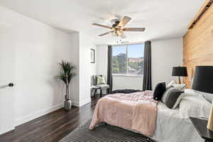Bedroom featuring wood finished floors, wooden walls, and ceiling fan