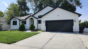 Ranch-style house with driveway, stucco siding, a front lawn, and a garage