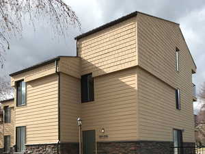 View of condominium exterior with stone siding and a lawn.  (Condominium includes Second & Third Level)