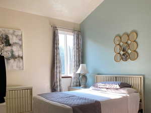 Master bedroom carpeted with vaulted ceiling.