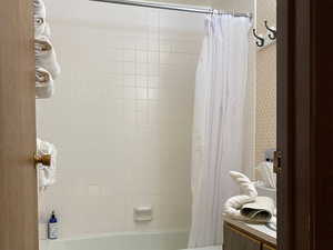 Typical Full bath featuring tile patterned floors, shower / bath combo with shower curtain, and a textured ceiling