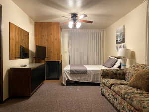 Carpeted bedroom (2nd Level) featuring wooden walls, a textured ceiling, and ceiling fan